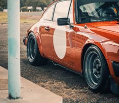 an orange car with white circles painted on it's side parked next to a pole