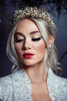 a woman with blonde hair wearing a tiara and makeup looks down at her face