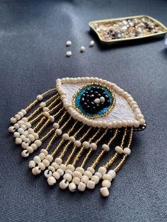 a close up of a brooch on a table with beads and other items in the background