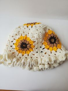 a white crocheted hat with yellow and brown flowers