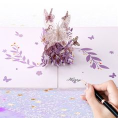 a person is writing on a piece of paper with flowers and butterflies in the background