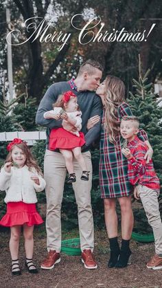 a family standing in front of a christmas tree with their two children and one adult