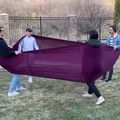 some people are carrying a large purple object in the grass and one person is holding it