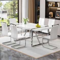 a dining room table with white chairs and a fruit bowl on the top of it