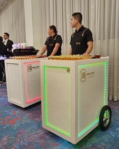 two men in uniform are standing behind a table with cakes on it and lit up wheels