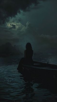 a person sitting in a boat on the water under a dark sky with storm clouds