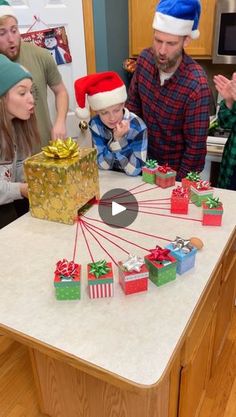 a group of people standing around a kitchen counter with presents on it and one person holding a present