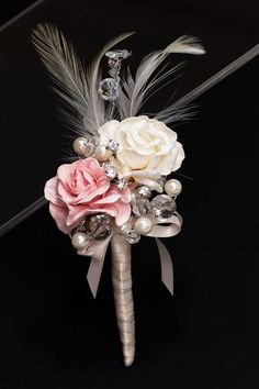 a bridal bouquet with flowers and feathers on a black background for a wedding or special occasion