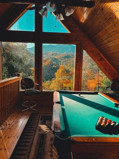 a pool table in the middle of a room with large windows looking out on mountains