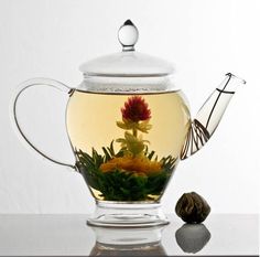 a glass tea pot filled with water and flowers