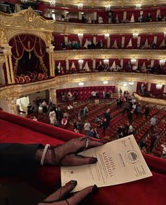 a person holding up a piece of paper in front of an auditorium filled with people