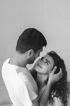 black and white photograph of a man kissing a woman's face on the bed