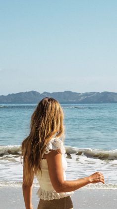 a woman standing on top of a beach next to the ocean