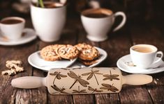 some cookies and coffee are sitting on a wooden table with dragonflys painted on them