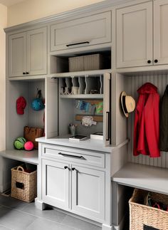 an organized mud room with gray cabinets and baskets