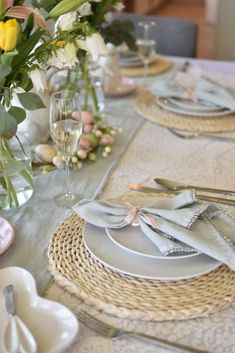 a table set with place settings and flowers in vases