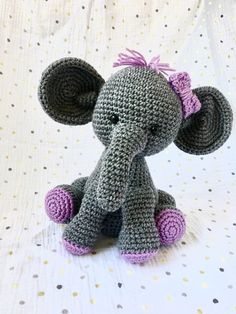 a small crocheted elephant sitting on top of a white table covered with polka dots