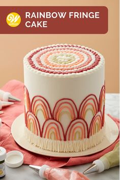 there is a cake with icing on it and the words, rainbow fringe cake