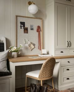 a white desk with a chair and some pictures on the wall next to it in a room