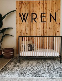 a baby crib in front of a wooden wall with the word wrenn written on it