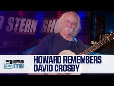 an older man with long hair and beard playing a guitar in front of a sign that reads howard remembers david crossby