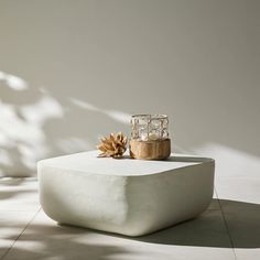 a white table topped with a vase and a pine cone sitting on top of it