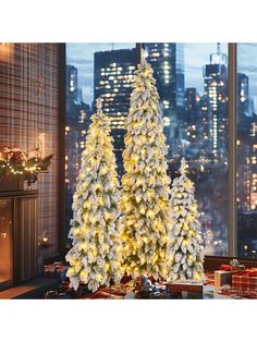 two white christmas trees in front of a window with city lights and presents on the floor