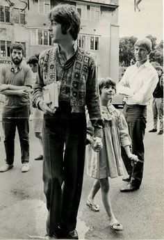 an old black and white photo of people walking down the street with one person holding his hand