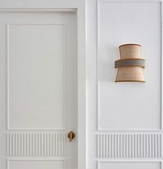 a white room with two lamps on the wall and an open door to another room