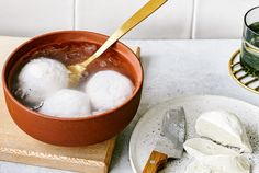 ice cream is being poured into a bowl on a wooden cutting board next to a glass of green tea