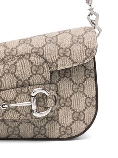 Find GUCCI 1955 Horsebit Shoulder Bag on Editorialist. The Gucci 1955 Horsebit Shoulder Bag is crafted from GG Supreme canvas with calf leather details. This mini shoulder bag features a Horsebit detail, a detachable shoulder strap, a detachable chain-link shoulder strap, a flap closure, and a main compartment with a logo patch. The bag has a canvas lining and silver-tone hardware. It is an asymmetrical design with a flap open closure and a turn lock. The bag can be worn on the shoulder or crossbody. Gucci Travel Shoulder Bag With Horsebit Detail, Gucci Shoulder Bag With Horsebit Detail For Travel, Vintage Gucci Coated Canvas Shoulder Bag, Vintage Shoulder Bag With Horsebit Detail For Everyday, Vintage Shoulder Bag With Horsebit Detail, Gucci Satchel Shoulder Bag With Horsebit Detail, Gucci Crossbody Bag With Horsebit Detail, Designer Satchel Shoulder Bag With Horsebit Detail, Luxury Satchel Shoulder Bag With Horsebit Detail