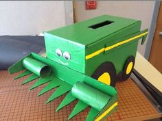 a green box with a face on it sitting on top of a table next to a piece of cardboard