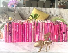 a bunch of books sitting on top of a table next to a vase filled with flowers