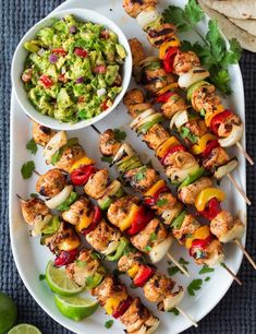 chicken kabobs on skewers with guacamole and salsa