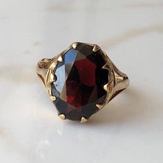 A Vintage 9 carat yellow gold Garnet ring. This beautiful piece holds a large deep red stone in a gold setting. CONDITION: Wear consistent with age and use. Please see photos for more detail. HALLMARKED 9 CARAT GOLD, ASSAYED IN LONDON 1977 STONE SIZE (SETTING): 14mm x 11mm  SETTING HEIGHT: 5mm BAND WIDTH: 2mm RING SIZE: US: 6 | UK: L 1/4 WEIGHT: 3.2 grams (UZZ) Hessonite Ring, Gold Garnet Ring, Class Rings, Garnet Gem, Red Band, Garnet Ring, Lovely Ring, Garnet Rings, Red Stone