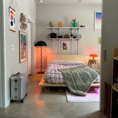 a bedroom with a bed, lamp and pictures on the wall