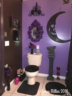 a bathroom decorated in purple and black with halloween decorations on the wall above the toilet