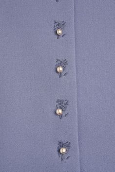 a blue shirt with flowers and pearls on it