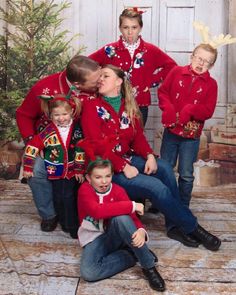 a group of children wearing ugly christmas sweaters posing for a family photo in front of a door