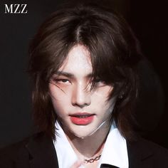 a man with long hair wearing a black suit and white shirt, red lipstick on his lips