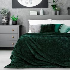 a bedroom with green bedding and plants on the nightstands, in front of a gray wall