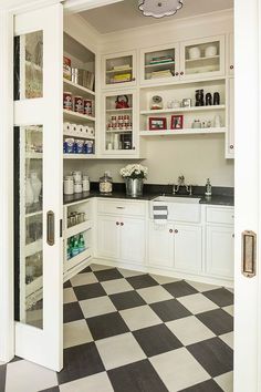 a kitchen with white cabinets and black and white checkered flooring on the floor