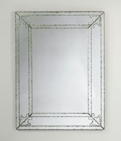 a square mirror hanging on the wall with an ornate frame around it's edges