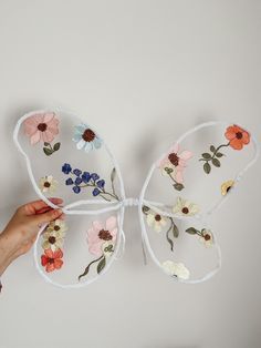 a person is holding up a butterfly made out of paper and fabric with flowers on it