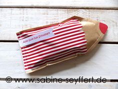 a red and white striped paper bag on top of wooden planks with a tag attached to it