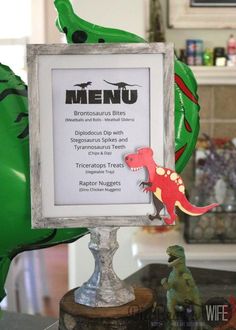 there is a sign that says menu with dinosaurs on it and balloons in the background