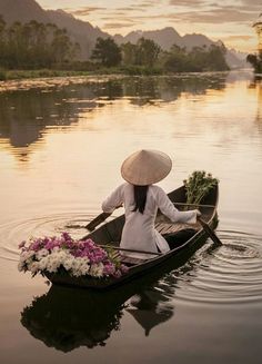 a woman in a boat with flowers on the water