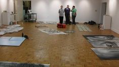 three women standing in an empty room with various pieces of art on the floor and covering them