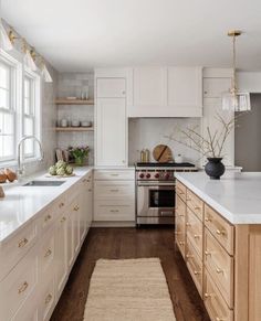 a large kitchen with white cabinets and wood flooring, along with an area rug