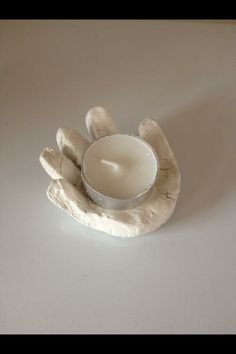 a white candle sitting on top of a wooden hand